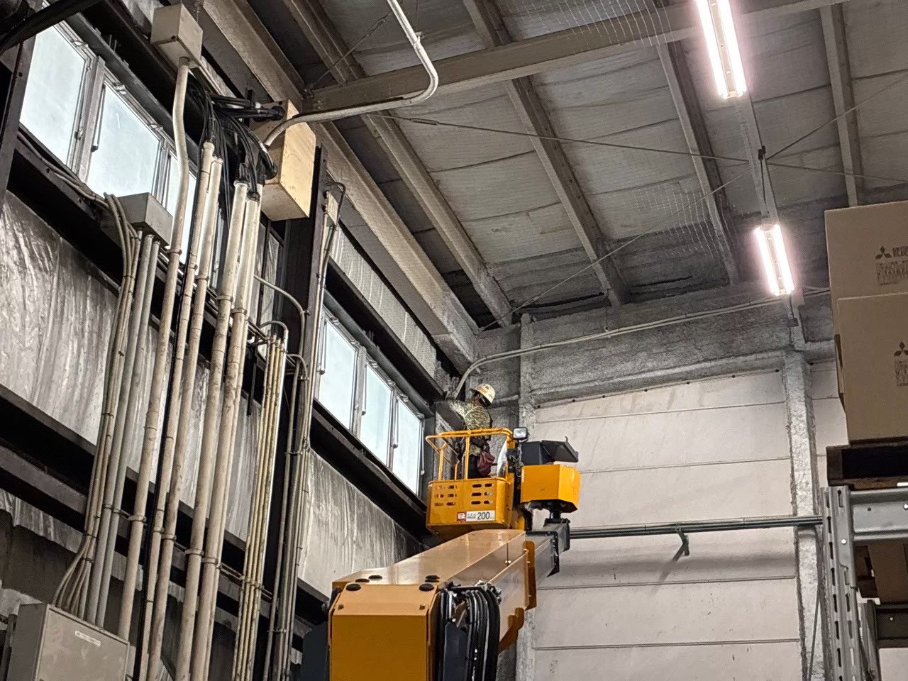 高所作業車から倉庫内上部の鉄骨フレームへの施工状況