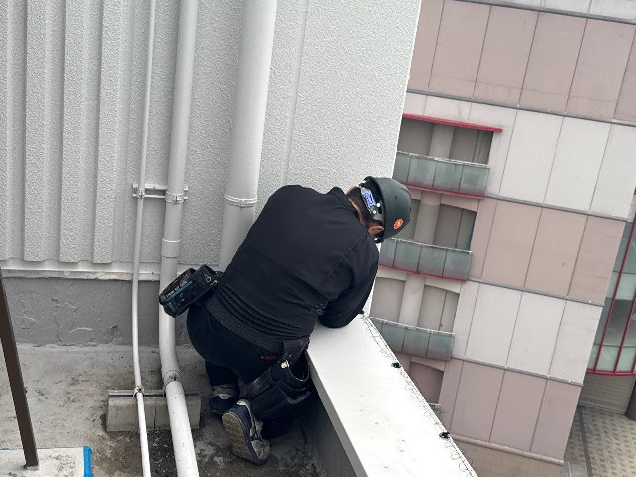 屋上パラペット・上部固定アンカーの施工：専用ドリルでアンカーを打ち込みネット固定の起点を設置