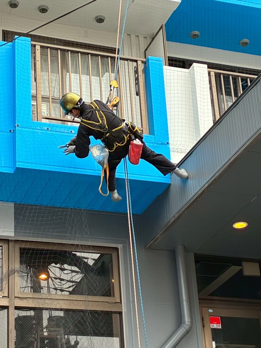 ベランダ庇部分へのロープアクセス施工：ネット固定金具の取り付けと位置調整