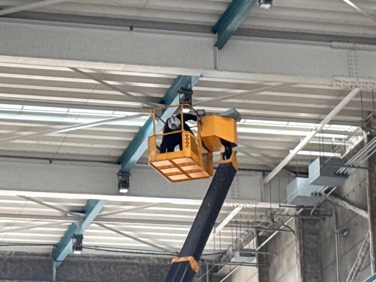 工場内天井付近の施工：高天井の鉄骨フレームへのネット張設作業